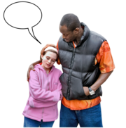A woman with her hands folded standing and talking to her friend. Her friend has his arm around her.