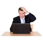 A man sits at his computer, scratching his head. 