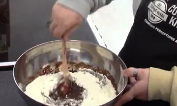 Someone holding a wooden spoon in a bowl of mixture.