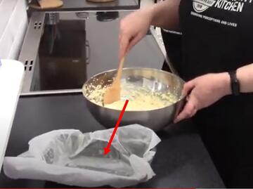 A mixing bowl with a spoon and a red arrow pointing to a tin.