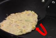 A spatula underneath the fritter and a red arrow in a semi circle.