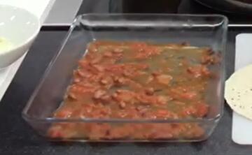 An ovenproof dish with some tomato mixture in the bottom of it.