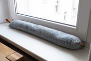 A draught excluder in front of a window.