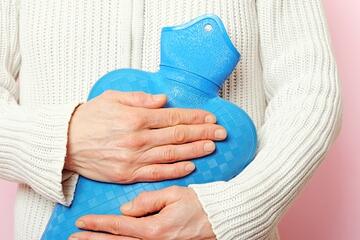 Someone holding a hot water bottle to the front of their jumper.