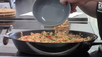 A bowl of lemon juice being tipped into a frying pan.
