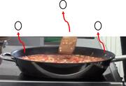 A frying pan of food with some red arrows pointing to bubbles above it.