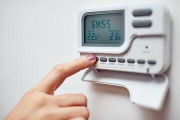 A finger on the buttons of a heating or hot water timer.