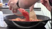 Chopped tomatoes being poured into a frying pan.