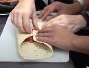 Hands holding a folded tortilla wrap.