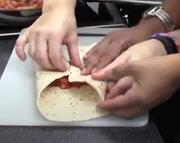 Hands holding a folded tortilla wrap. 