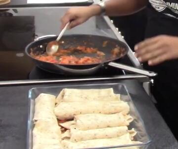 A dish of enchiladas and a frying pan with some tomato mixture in it.