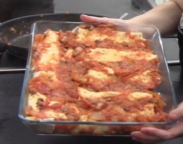A dish of enchiladas covered with tomato mixture.
