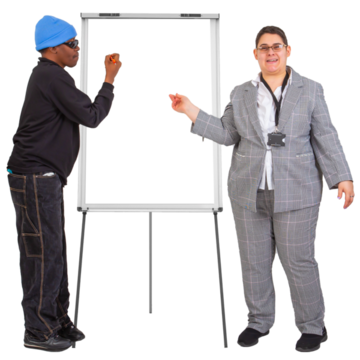 A man in a hat is writing on a flipchart next to a woman in a suit who is presenting training 
