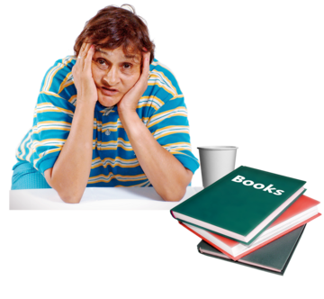 A woman has her elbows on a table and her head in her hands. On the table are a cup and books