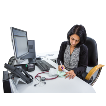 A doctor sitting at a desk writing on a pad. There is a computer and stethoscope in front of her. 