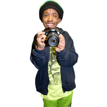 A man smiling and holding up a camera.
