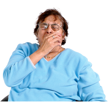 A woman is sitting down yawning with her hand to her mouth and her eyes closed