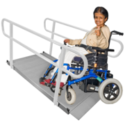 A woman in a wheelchair gives a thumbs up as she goes up a ramp