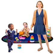 A childminder stands in front of a play mat where two children are playing
