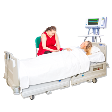 A woman looks sad sitting next to the hospital bedside of a woman who has died