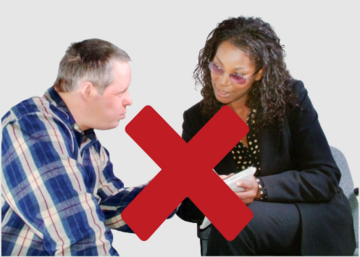 A man talking to his support worker with a red cross over them