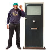 A man in a baseball hat is holding up some house keys next to a front door
