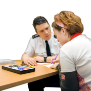 A woman is talking to a policeman at a desk in a meeting room