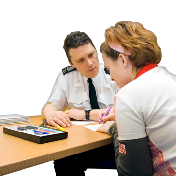 A woman is talking to a policeman at a desk in a meeting room