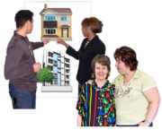 A woman with her arm around her friend in front of people choosing houses on a board