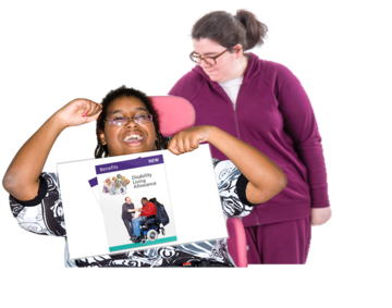 A carer has her arm around a woman in a wheelchair who is holding up a sign which shows the front cover of a disability living allowance leaflet