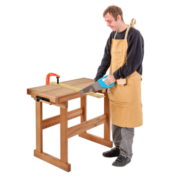 A man holding a saw and standing at a workbench