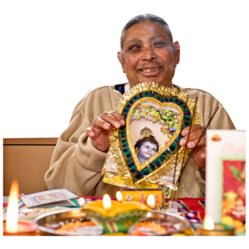An Asian woman holds up a Diwali decoration with candles on the table in front of her