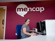 A Mencap Learning Disability Helpline adviser sitting at her desk