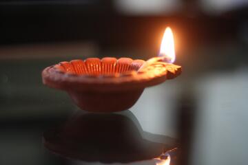 A clay lamp with a small flame burning