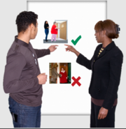 Two managers either side of a flip chart pointing to a picture with a green tick next to it of a two women as safe distance apart going into a room. Below that is a picture of a woman letting another woman into her house and both are near each other. This picture has a red cross next to it.