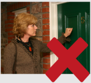 A woman visitor knocking on a front door with a red cross over the picture
