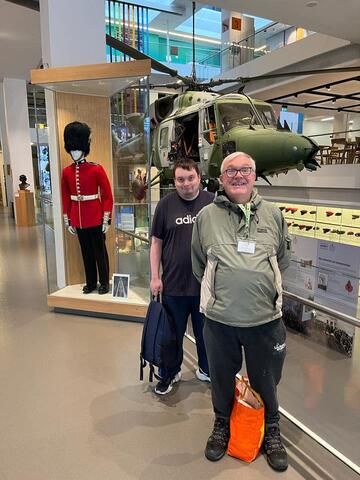 Two men stand next to a display case in a museum