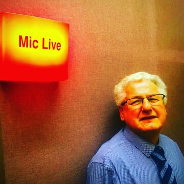 A man standing next to a sign that is lit up and says 'mic live'