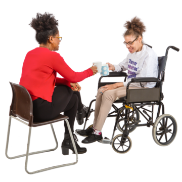 A support worker sits in front of a woman in a wheelchair, drinking coffee together.