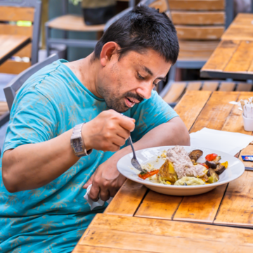 A man in a blue shirt eating a meal