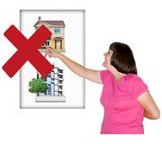 A woman with a learning disability is choosing a home from a poster with another home on it. The poster has a red cross over it