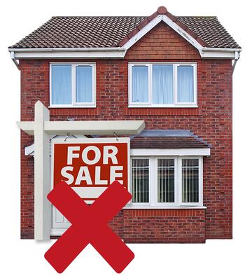 A home with a for sale sign outside with a red cross over it