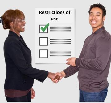 A picture of a list of restrictions of use on a wall between two people who are smiling and shaking hands