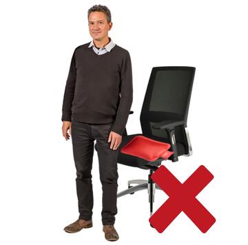 A man standing beside a chair which has a hot water bottle on it.  There is a red cross beside the image.