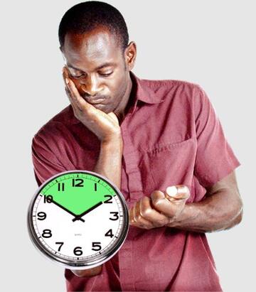 A man looking fed up with a clock in front of him