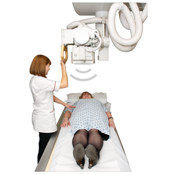 A patient lying on an X ray table with a member of hospital staff moving the x ray machine above them.