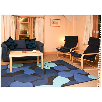 A lounge with a sofa, a table and 2 arm chairs.