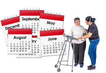A woman being helped to use a walking frame stands next to six months of calendar pages