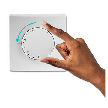 A hand turning down the temperature on a thermostat.