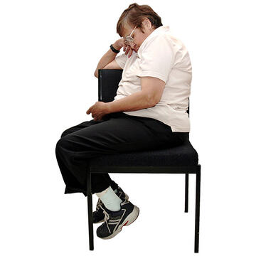 A lady sitting on a chair facing away with her head leaning on her hand.